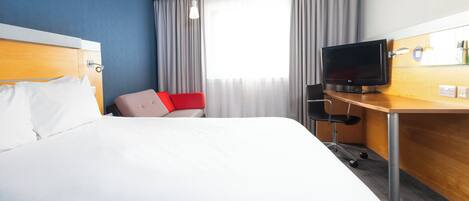Una camera d'albergo con un letto, una scrivania con televisione e una finestra con tende.