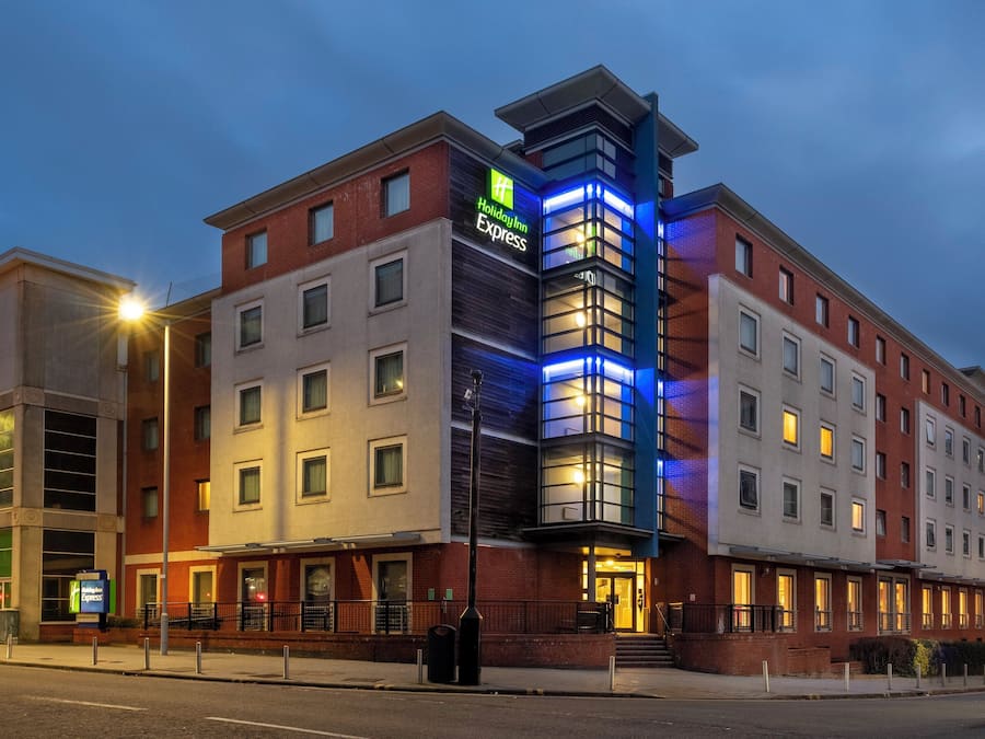 A Holiday Inn Express hotel with a modern design, featuring a prominent corner entrance and a mix of brick and glass facades.