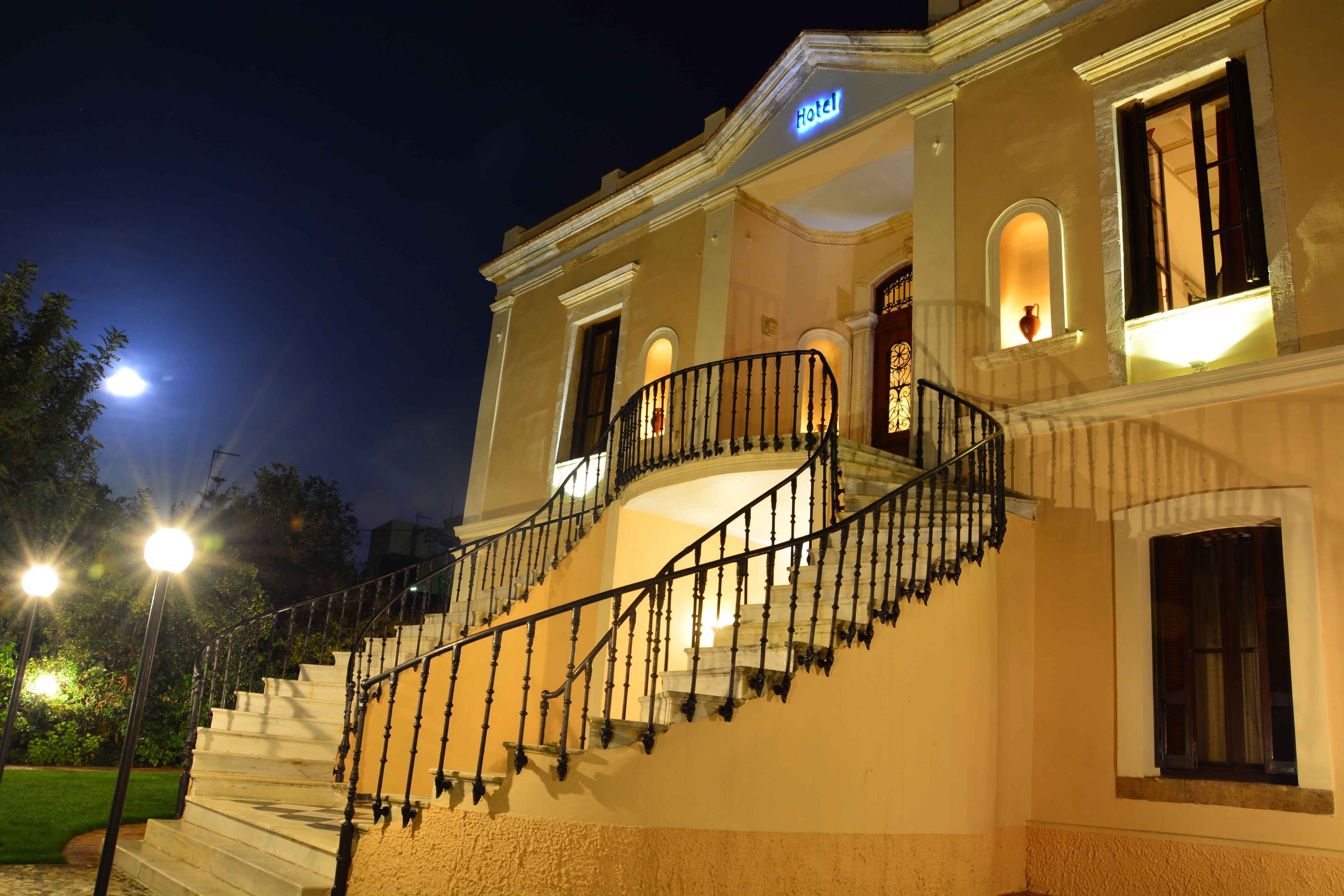 A hotel with a grand staircase leading to the entrance, a well-lit facade, and a clear night sky.