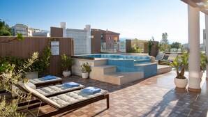 A rooftop pool area with lounge chairs, a hot tub, and potted plants. - Halepa Hotel (Chania)