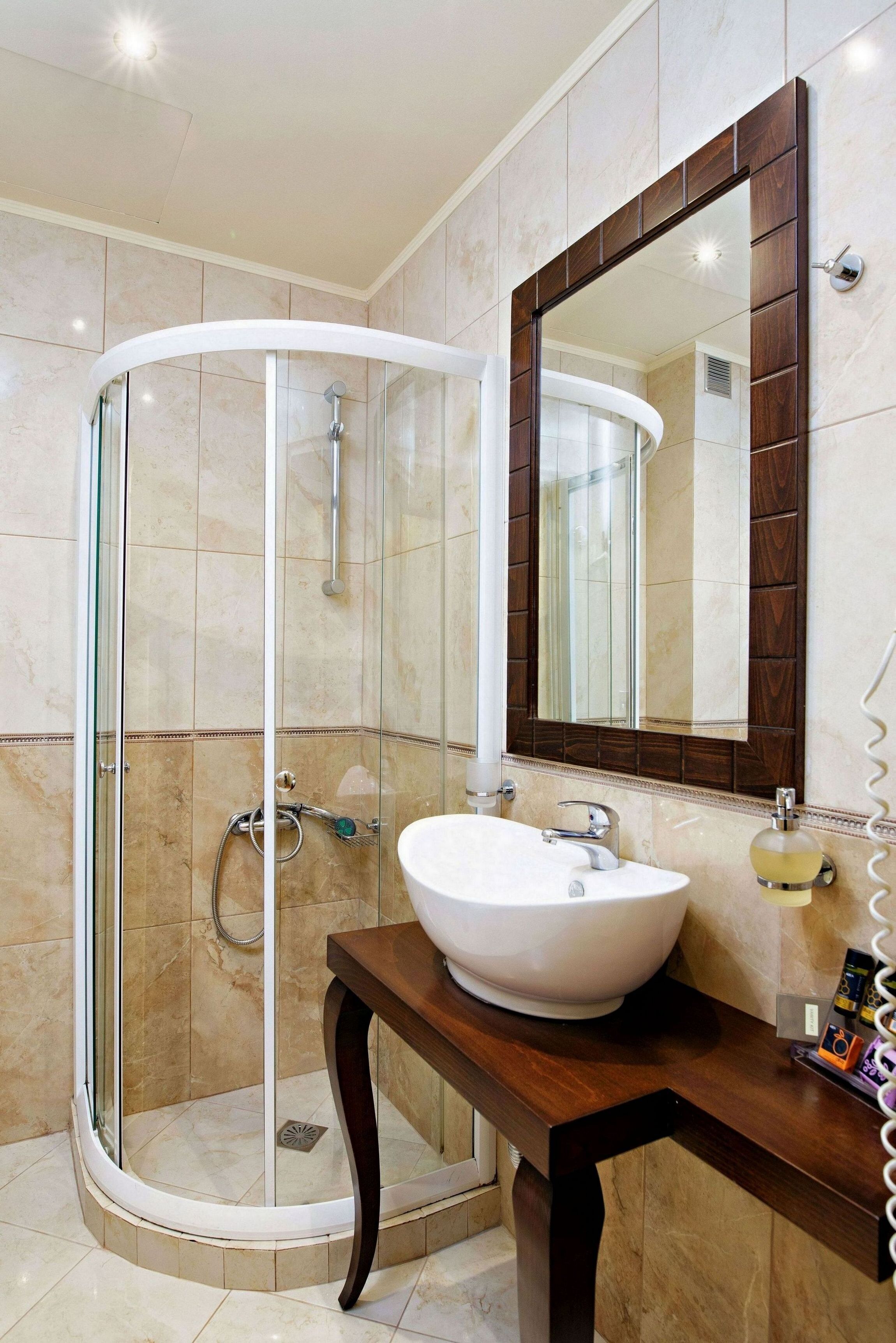 A modern bathroom with a glass-enclosed shower, a white sink, and a wooden vanity.