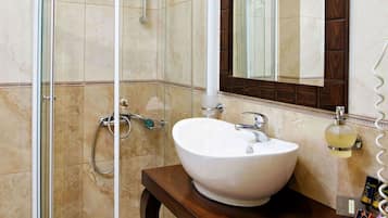 A modern bathroom with a glass-enclosed shower, a white sink, and a wooden vanity.