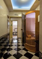 A hallway with a checkered floor, a sauna, and a treadmill in the background.
