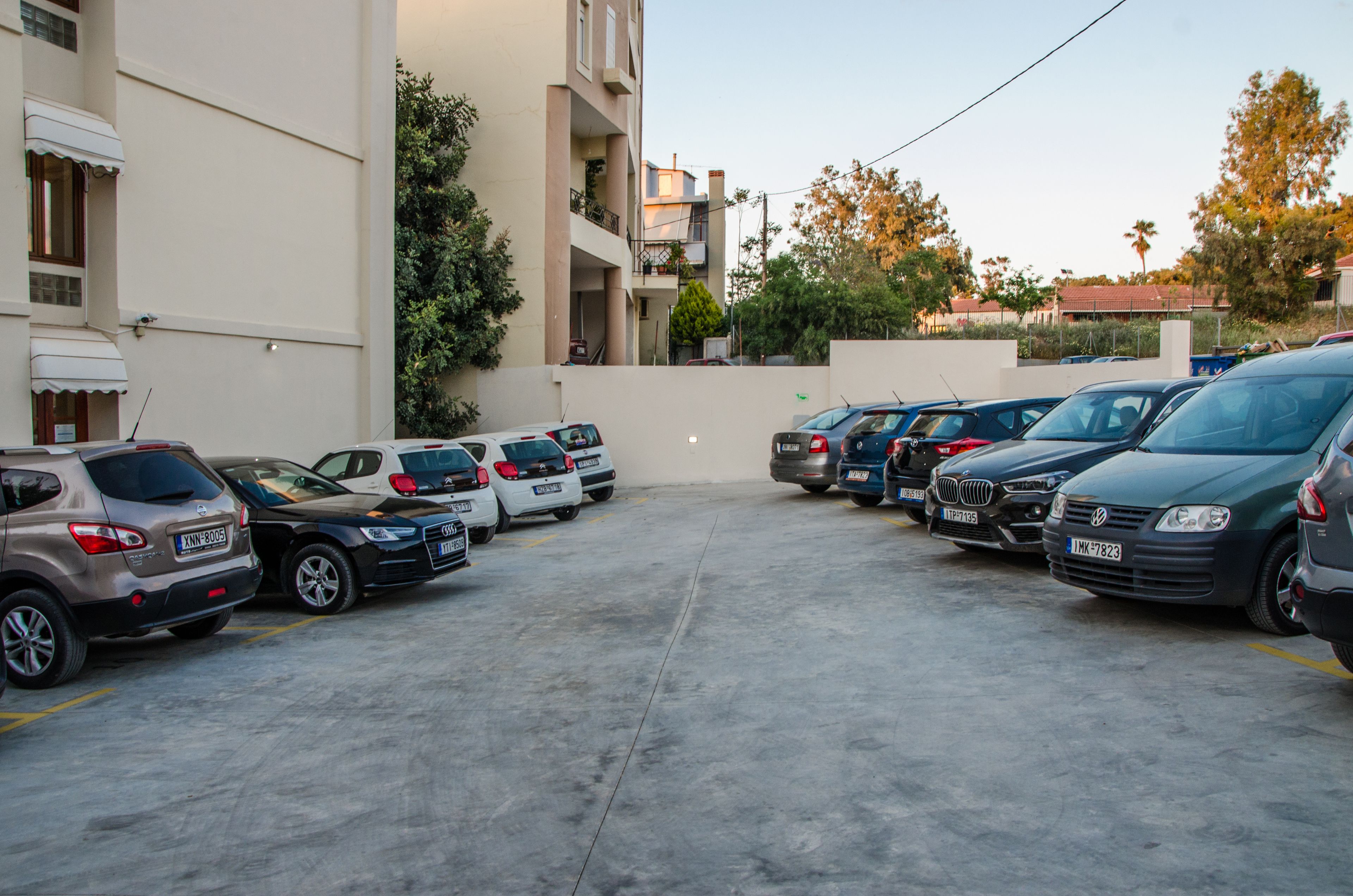 A parking lot with multiple cars parked in front of a building with balconies.