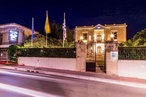 A hotel entrance with a gated driveway, a sign indicating the hotel name, and two flags.
