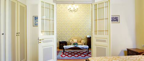 Una habitación de hotel con una cama, una silla, una mesita y un papel tapiz estampado.