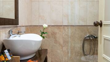 Un baño con un lavamanos grande de color blanco, un espejo y una zona de ducha.