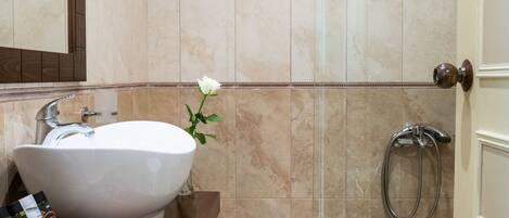 Un baño con un lavamanos grande de color blanco, un espejo y una zona de ducha.