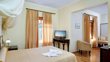 Una habitación de hotel con cama, televisión, escritorio, silla y cortinas.