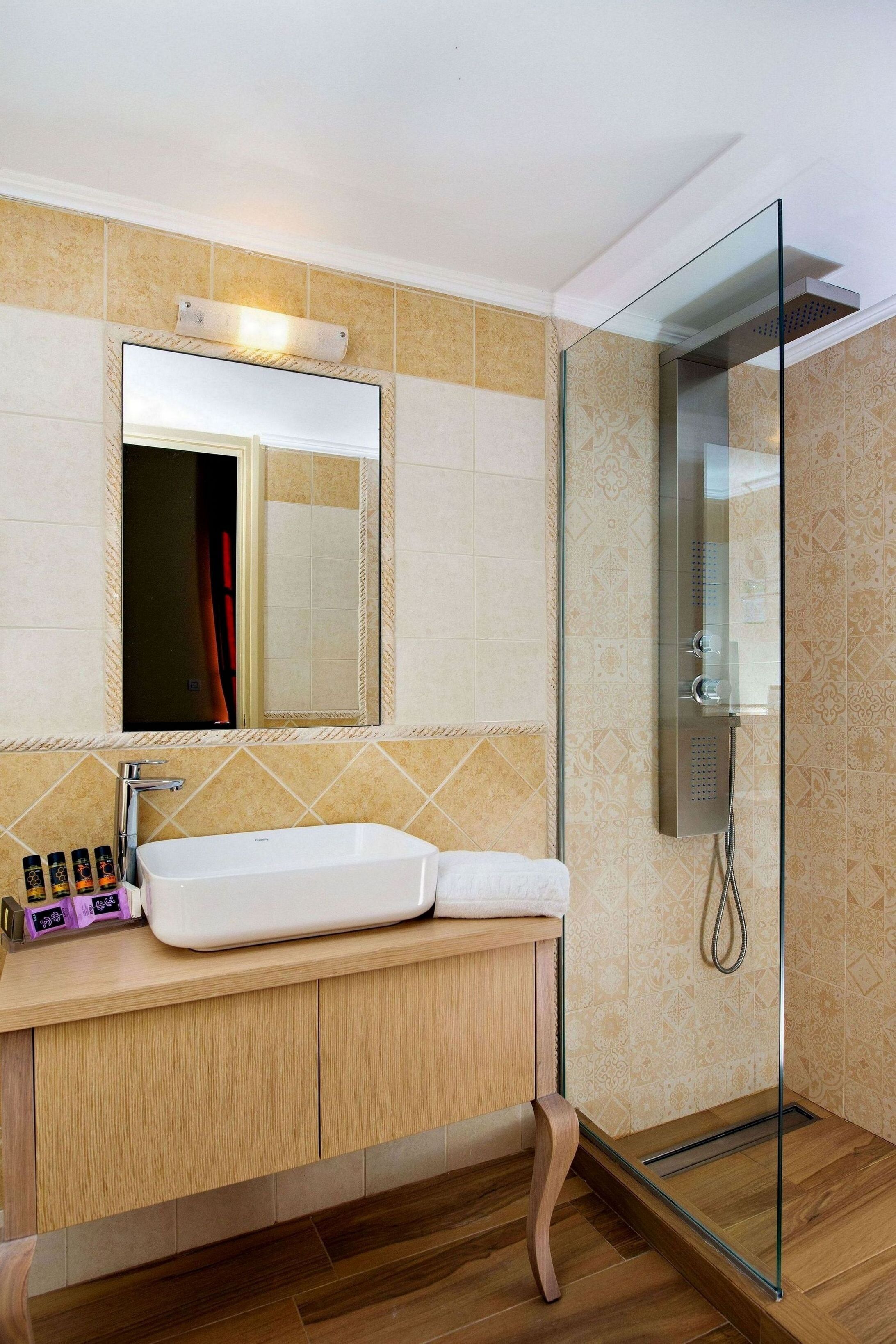 Une salle de bain moderne avec une douche à parois de verre, un lavabo blanc et un miroir au-dessus.