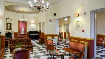 Un vestíbulo de hotel con piso de cuadros, candelabros ornamentales y muebles clásicos.