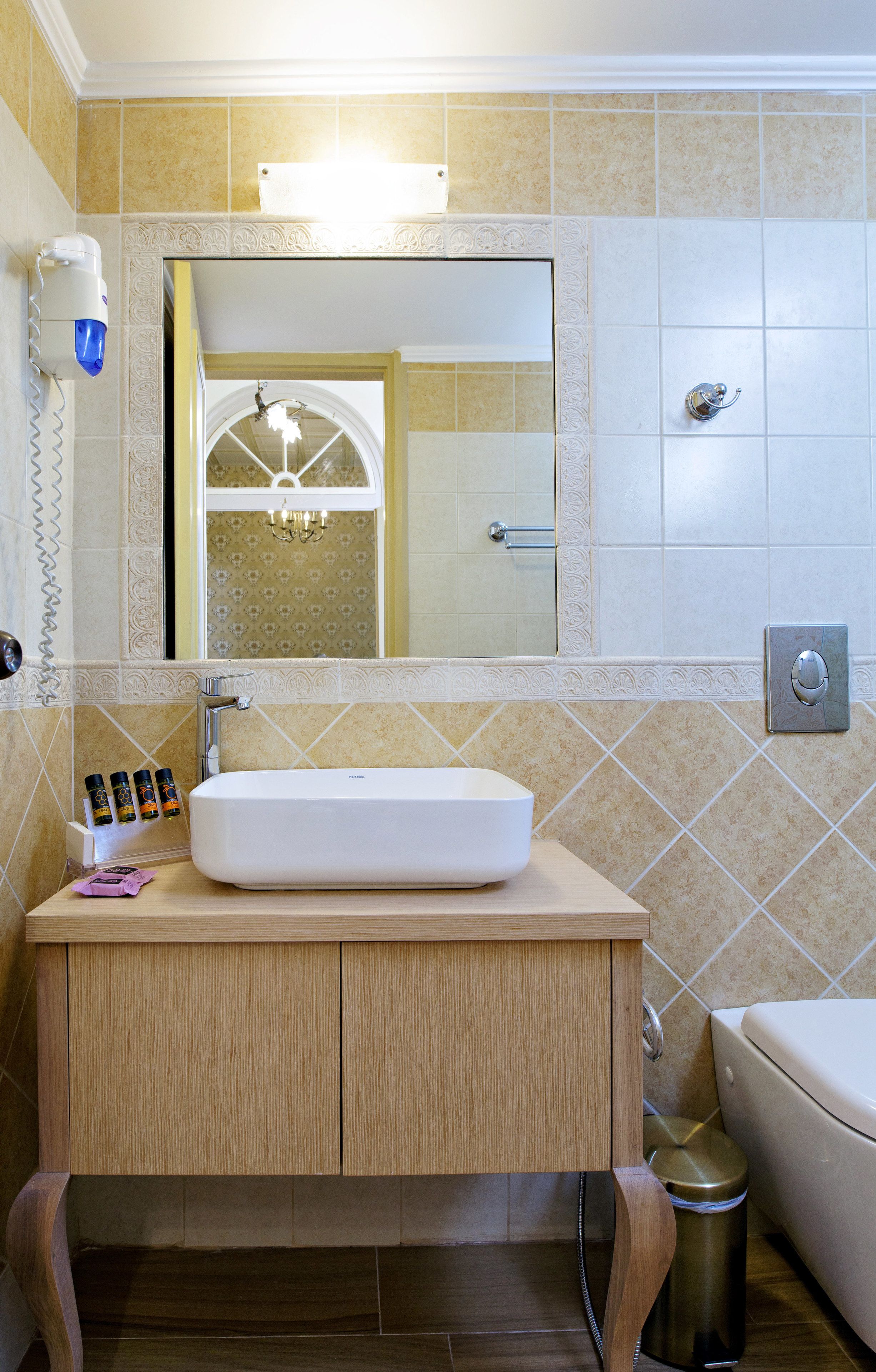 A bathroom with a white sink, wooden vanity, and a mirror above it.