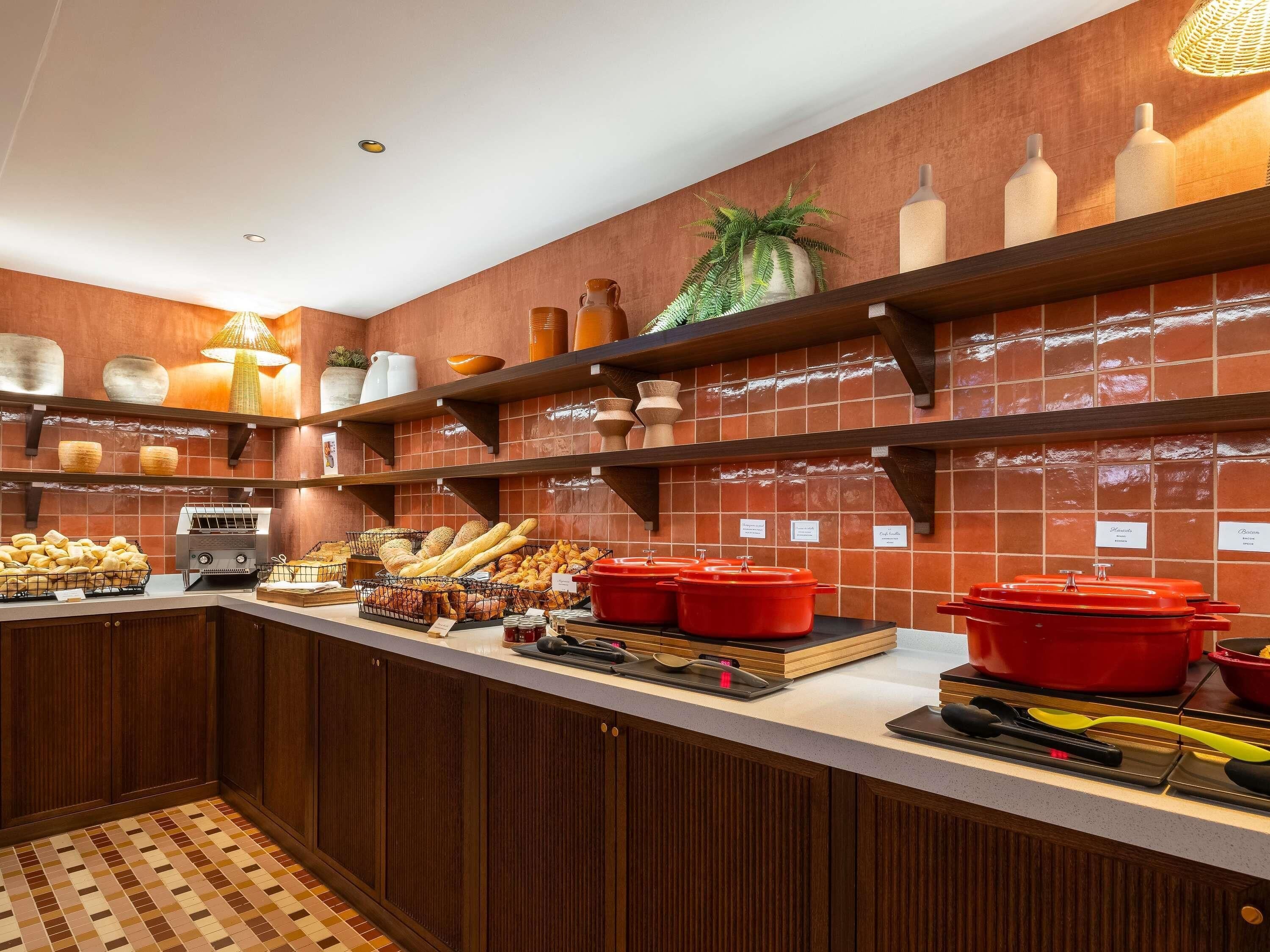Una cocina con armarios de madera, salpicadero de azulejos y diversos alimentos exhibidos en estantes y encimeras.