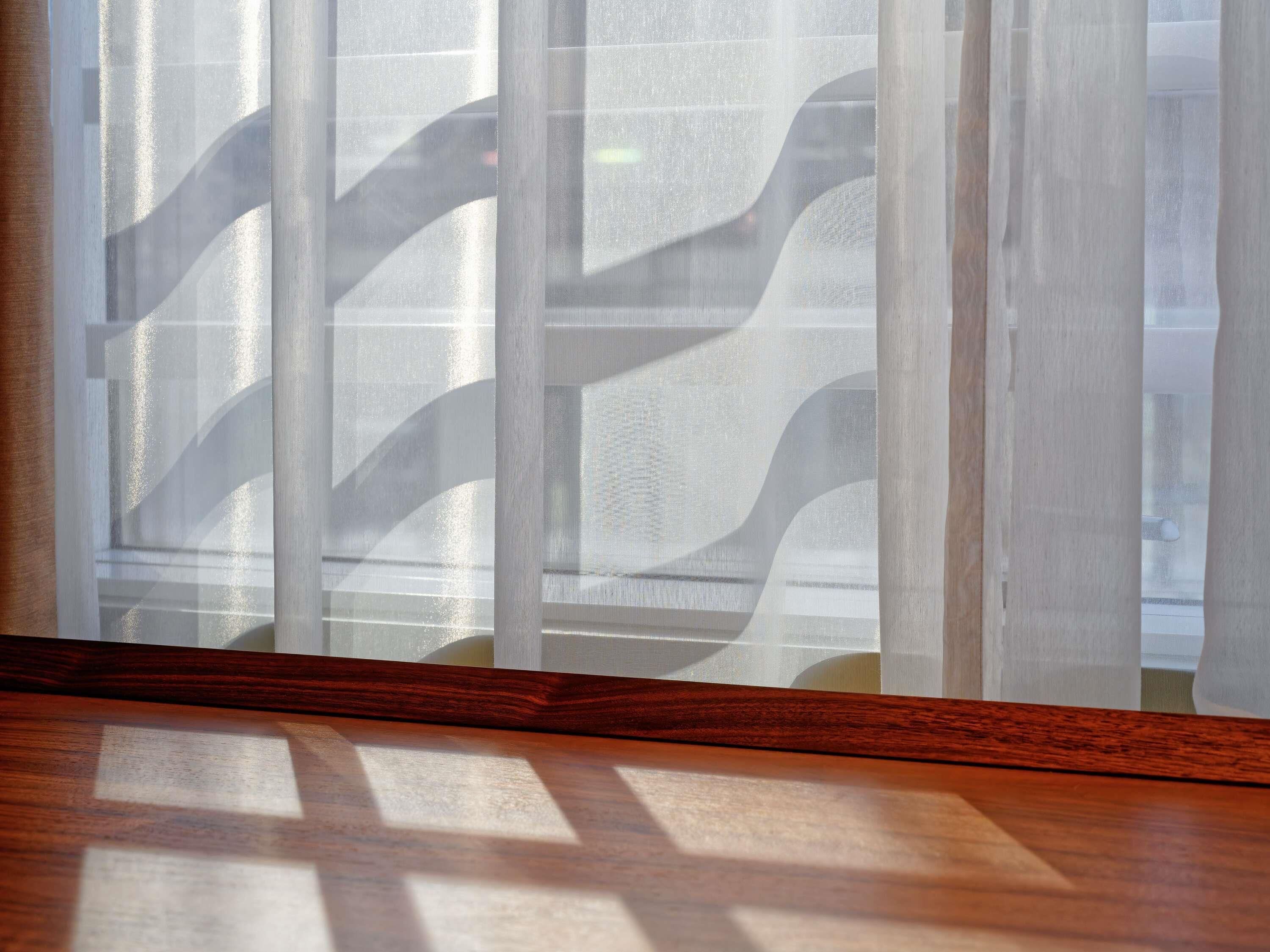 A window with a patterned blind and a wooden floor.