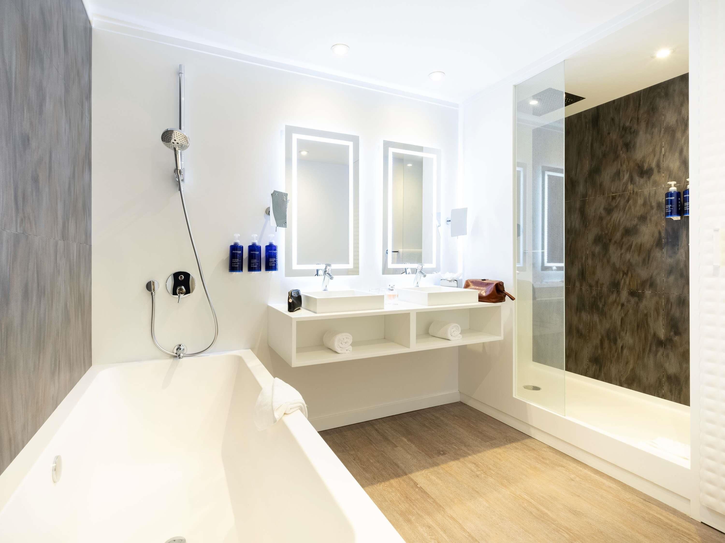 Un baño moderno con una bañera grande, dos lavamanos y un espejo amplio.