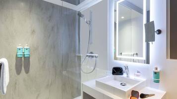 A modern bathroom with a glass shower enclosure, a white sink, and a large mirror.