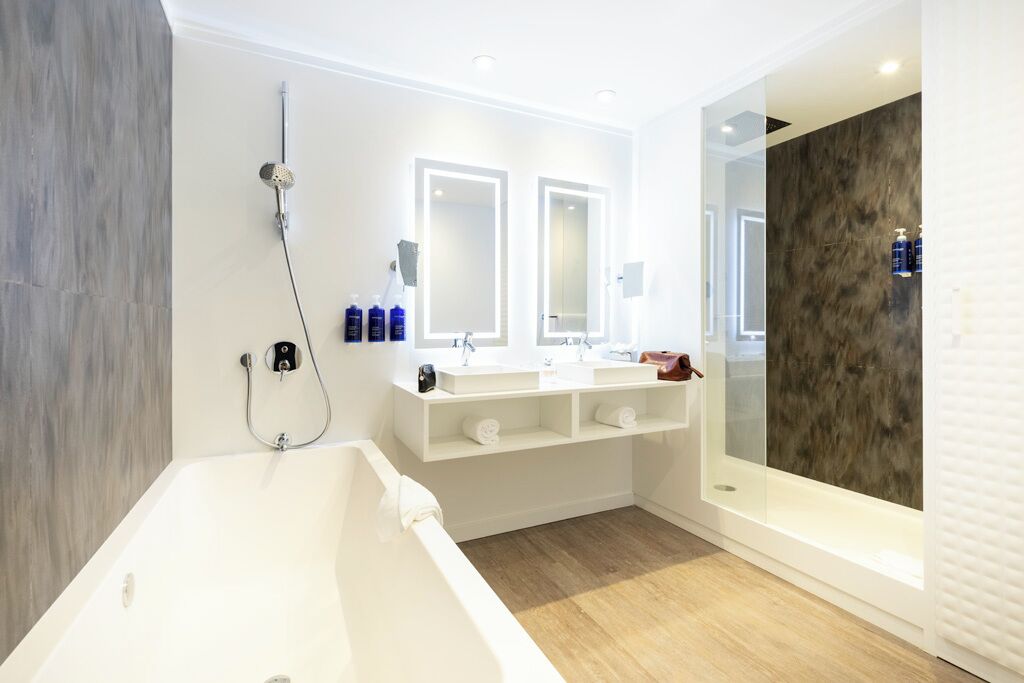 A modern bathroom with a bathtub, two sinks, and a large mirror.