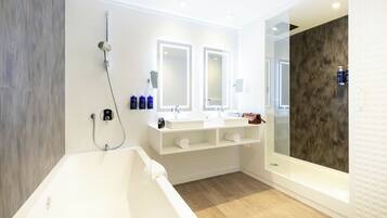 A modern bathroom with a bathtub, two sinks, and a large mirror.