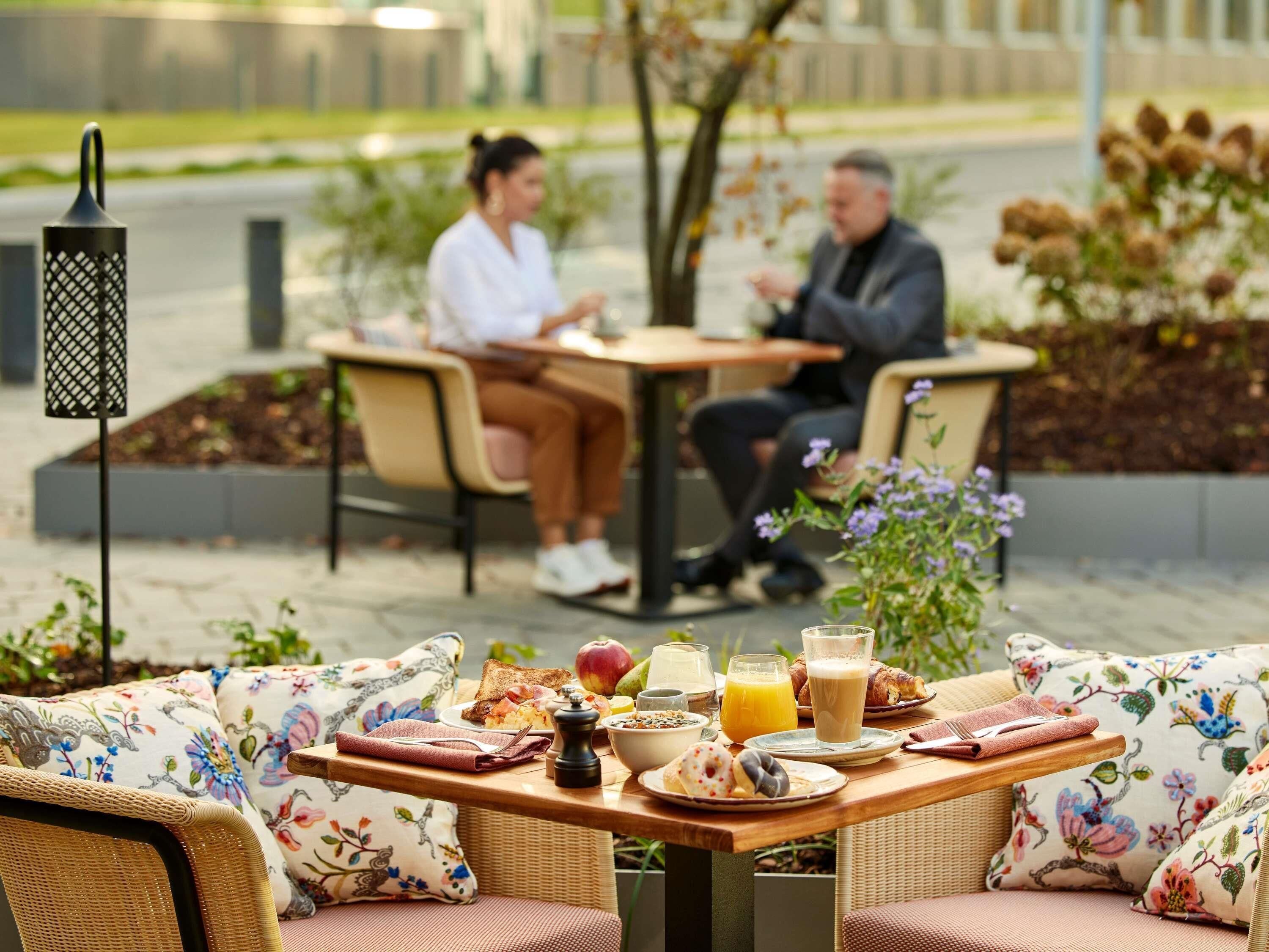An outdoor dining area with wicker furniture and floral cushions.