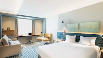 Una habitación de hotel moderna con una cama grande, un escritorio, una silla y un sofá.