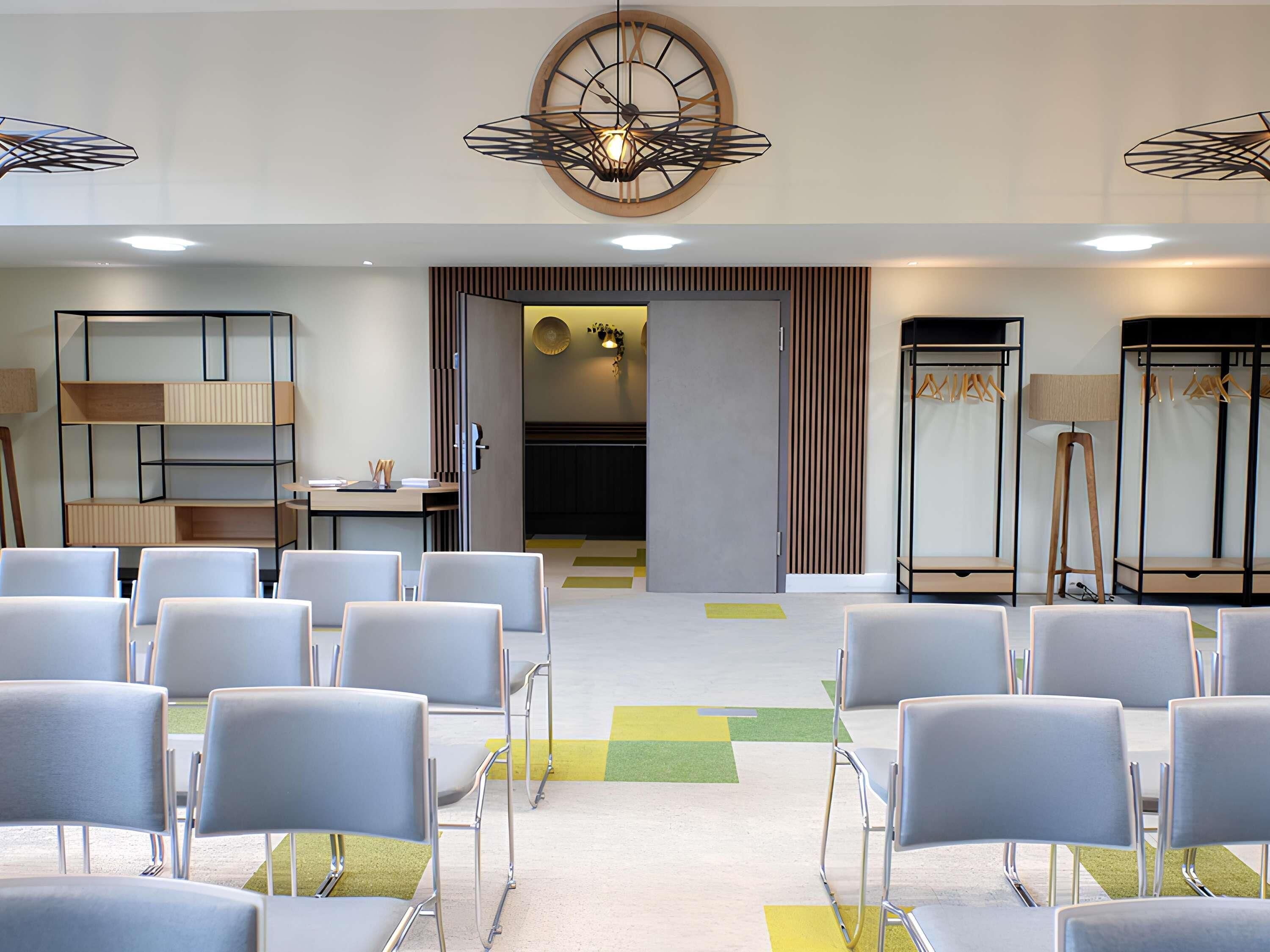 A conference room with chairs, a clock, a wardrobe, and a lamp.