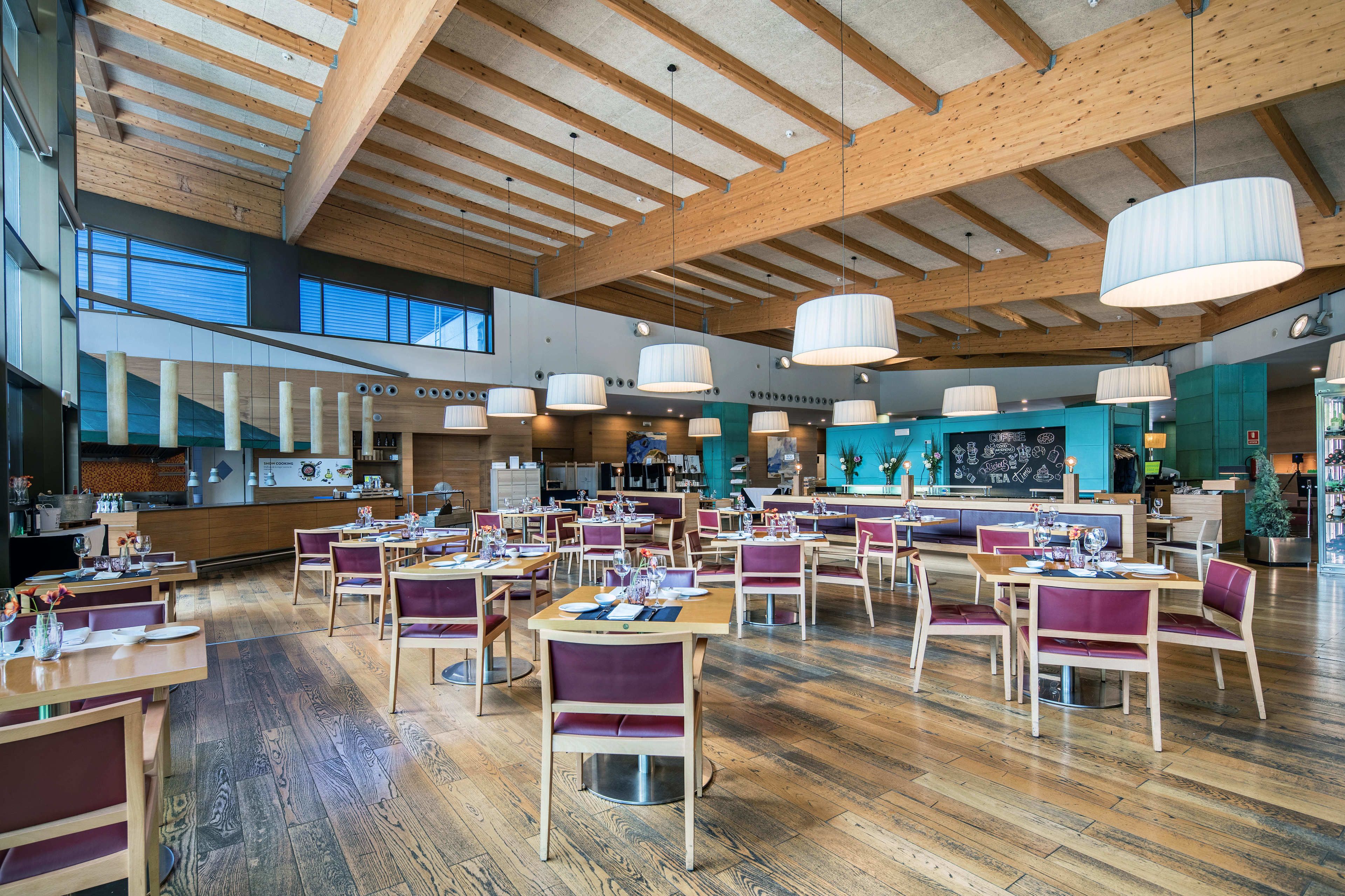 Un restaurante espacioso con vigas de madera, grandes lámparas colgantes y una zona de bar central.