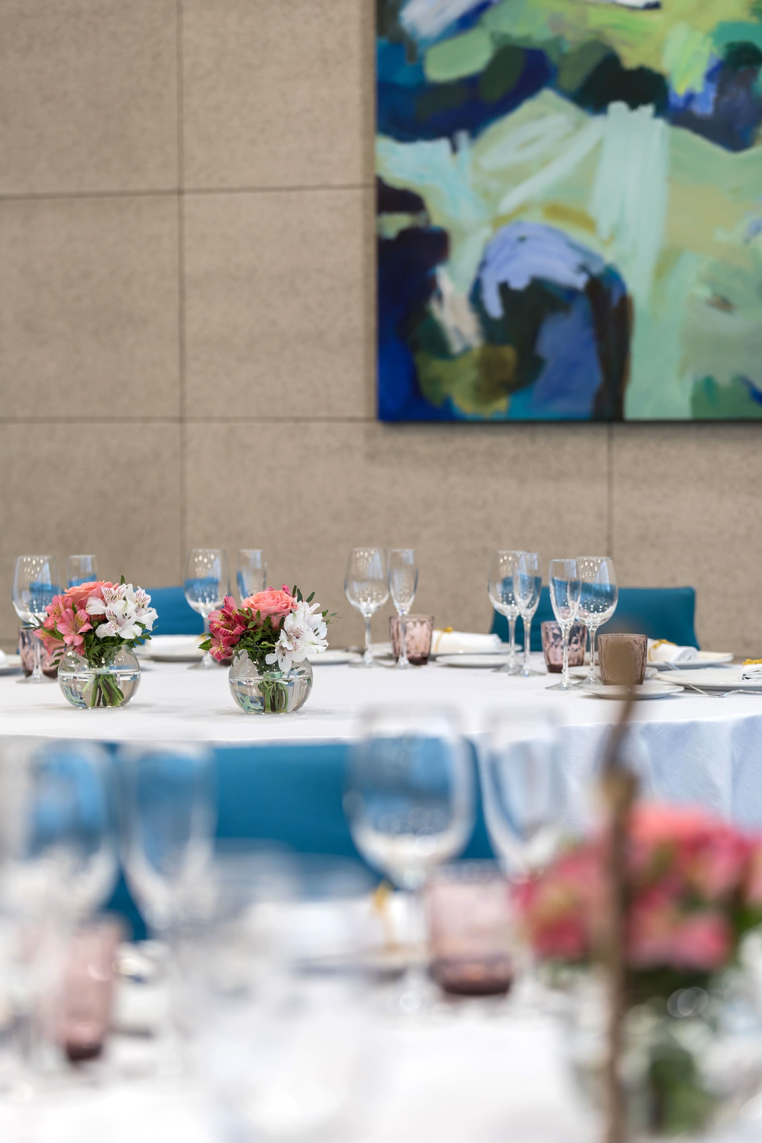 Een eettafel gedekt met glazen en een bloemstuk in het midden.