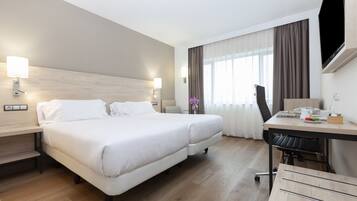 Una habitación de hotel con cama, escritorio, silla y televisor.