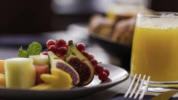 A plate of assorted fruits and a glass of orange juice on a table.