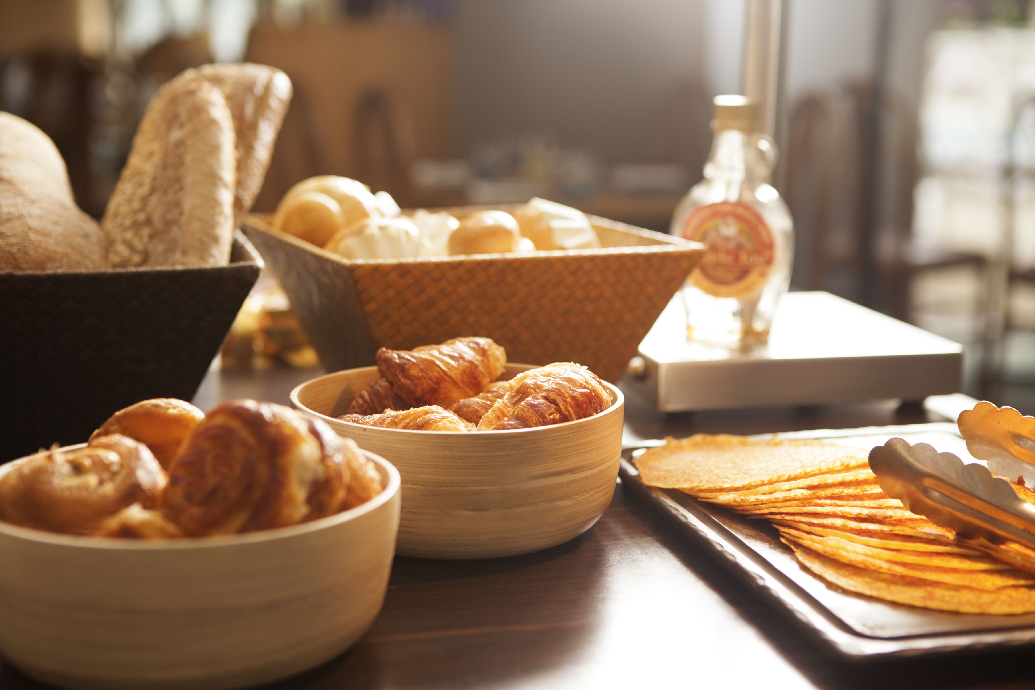 A variety of baked goods including bread, croissants, and pastries arranged on a wooden table.