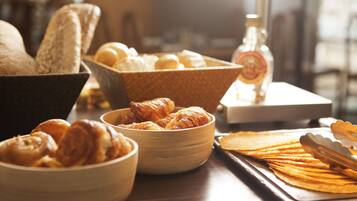 A variety of baked goods including bread, croissants, and pastries arranged on a wooden table.
