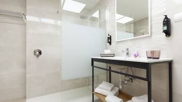 A modern bathroom with a glass-enclosed shower, a white sink with a black countertop, and a large mirror.