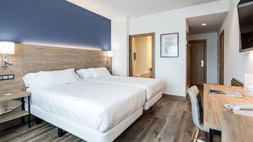 A modern hotel room with a large bed, bedside tables, a desk with a chair, and a TV mounted on the wall.