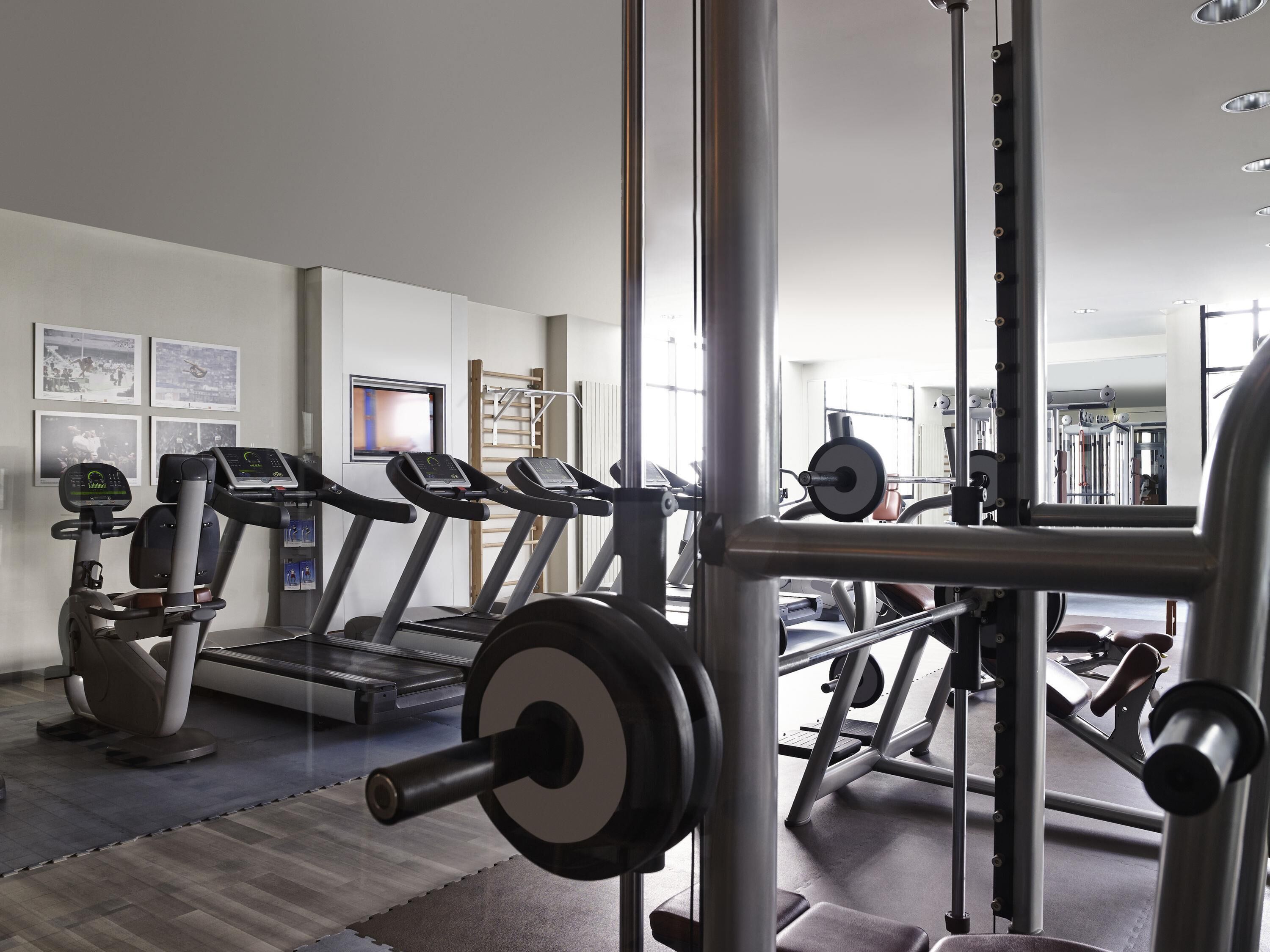 A gym with treadmills, weight machines, and a mirrored wall.