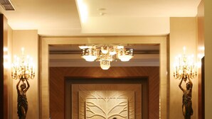 A hotel lobby with a polished floor, a central chandelier, and decorative candelabras. - Novotel Semarang (Semarang)