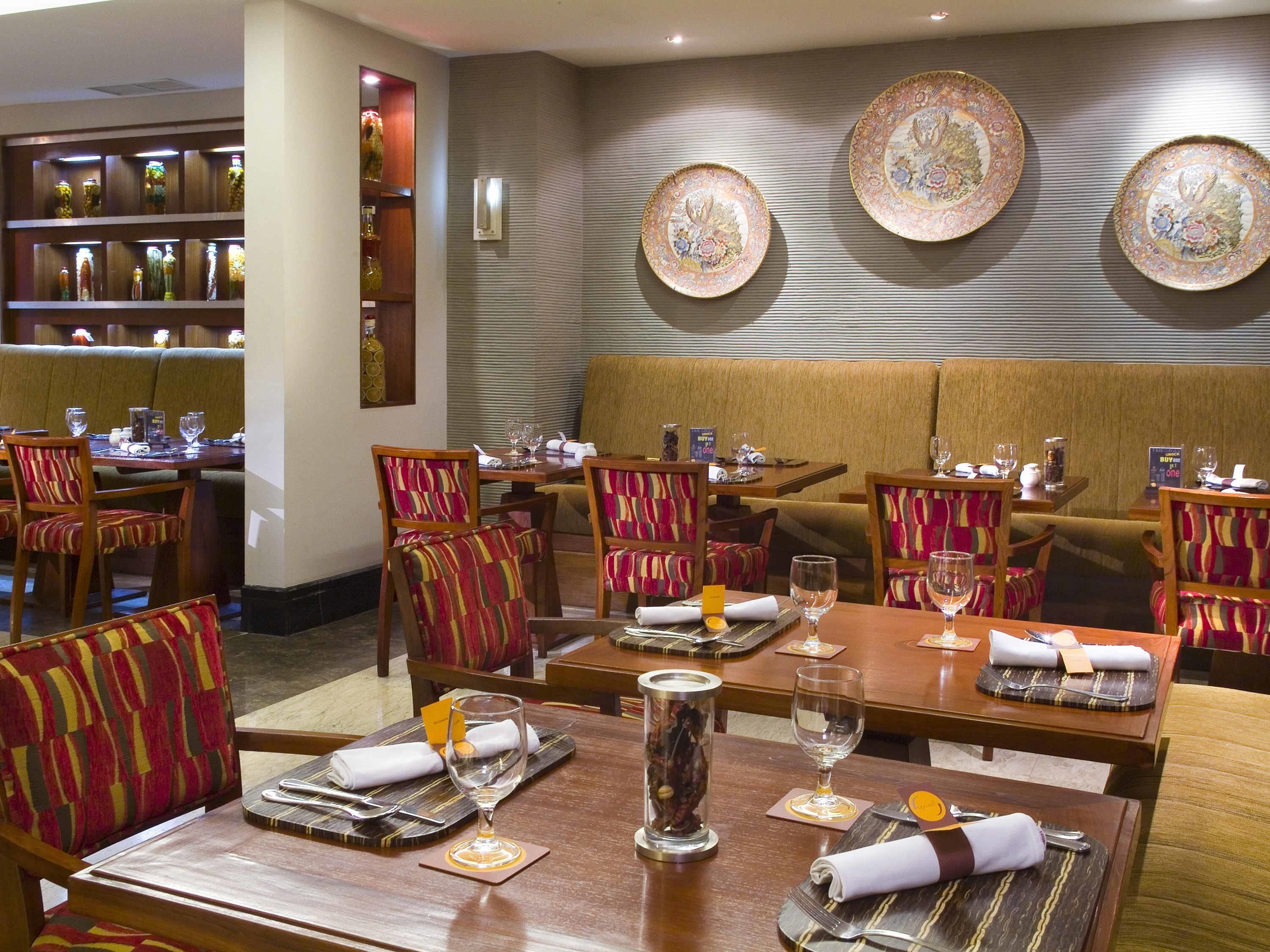 A restaurant with booths and tables, each set with cutlery, glasses, and napkins.