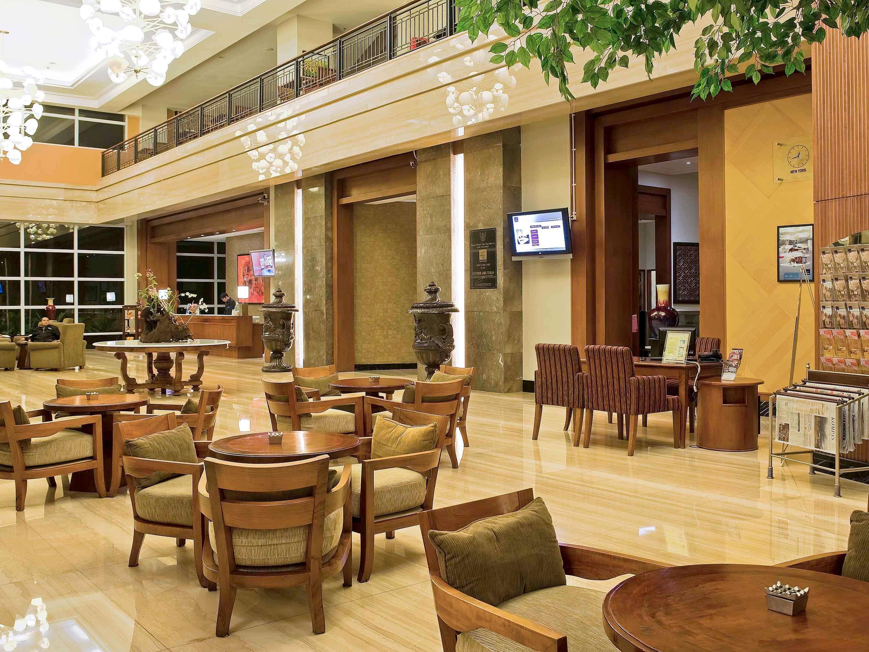A spacious lobby with multiple seating areas, a reception desk, and a television screen.