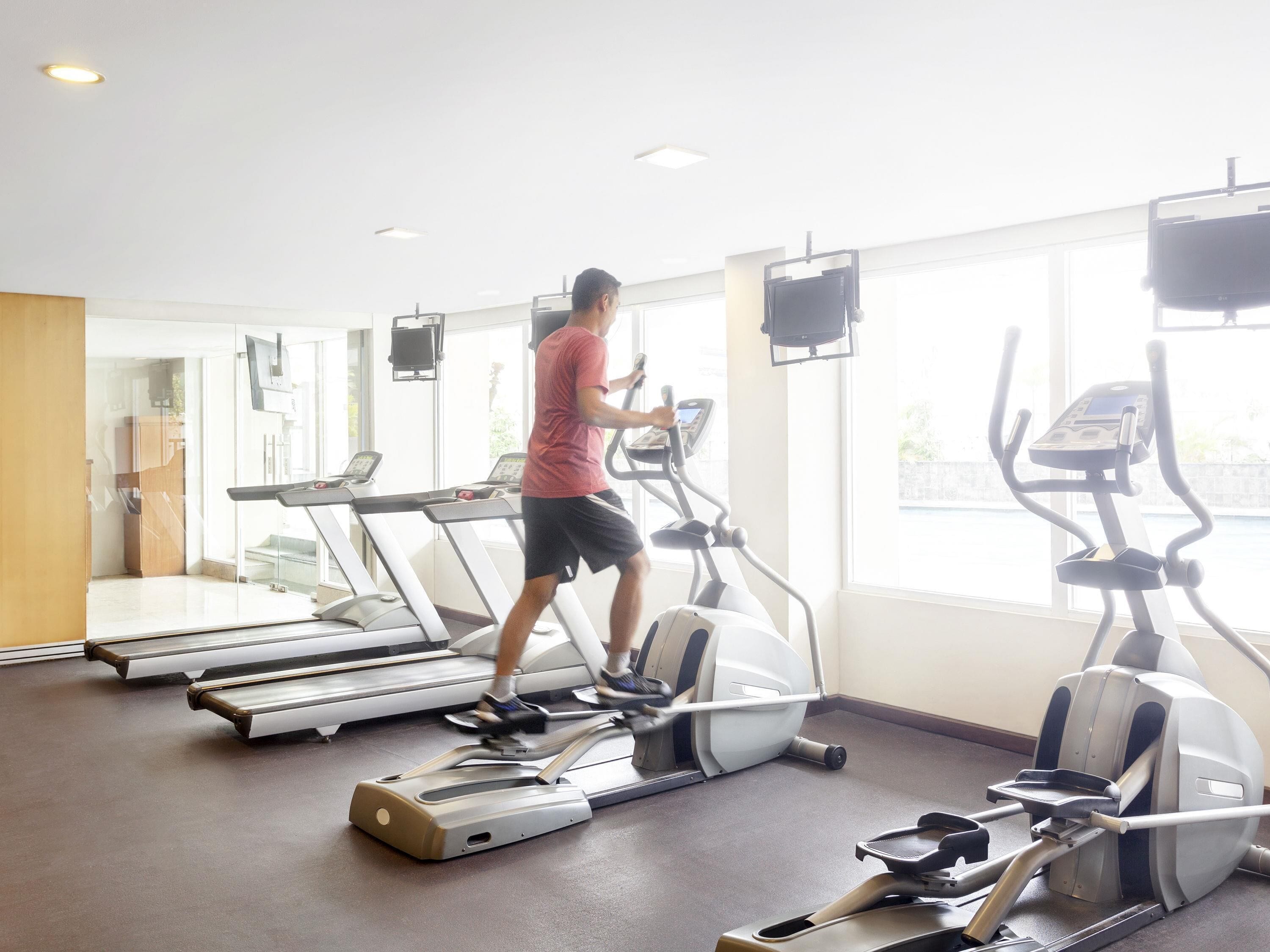 A gym with treadmills, elliptical machines, and a person using a treadmill.