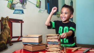 A child playing with wooden blocks and a toy car on a red table.