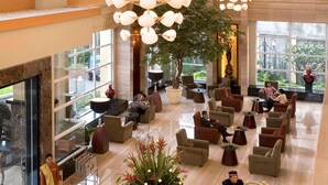 A spacious lobby with multiple seating areas, a central floral arrangement, and large windows offering views of the outdoors. - Novotel Semarang (Semarang)
