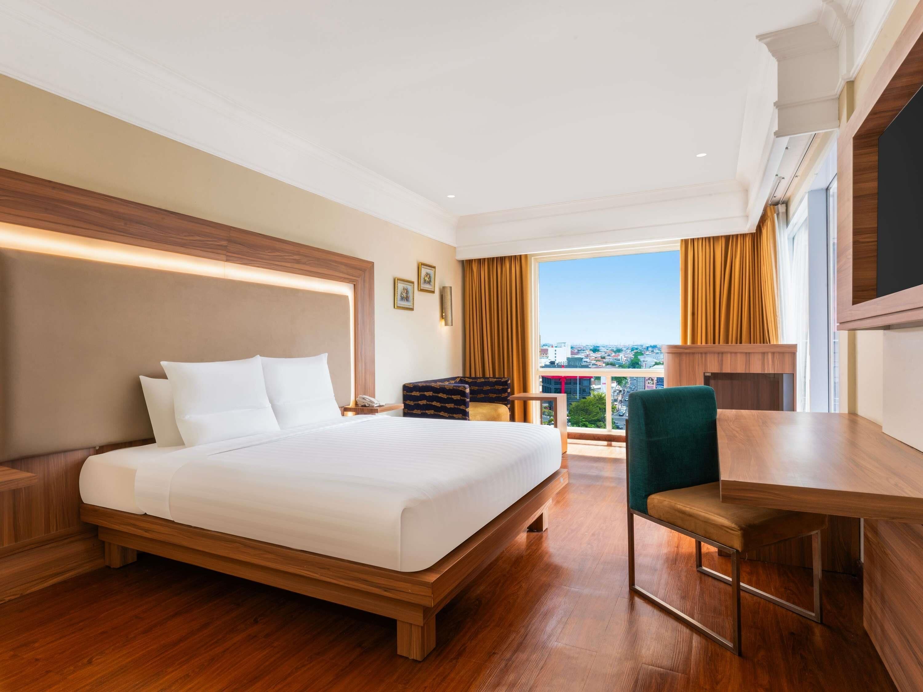 Een hotelkamer met een groot bed, een bureau en uitzicht op de stad.