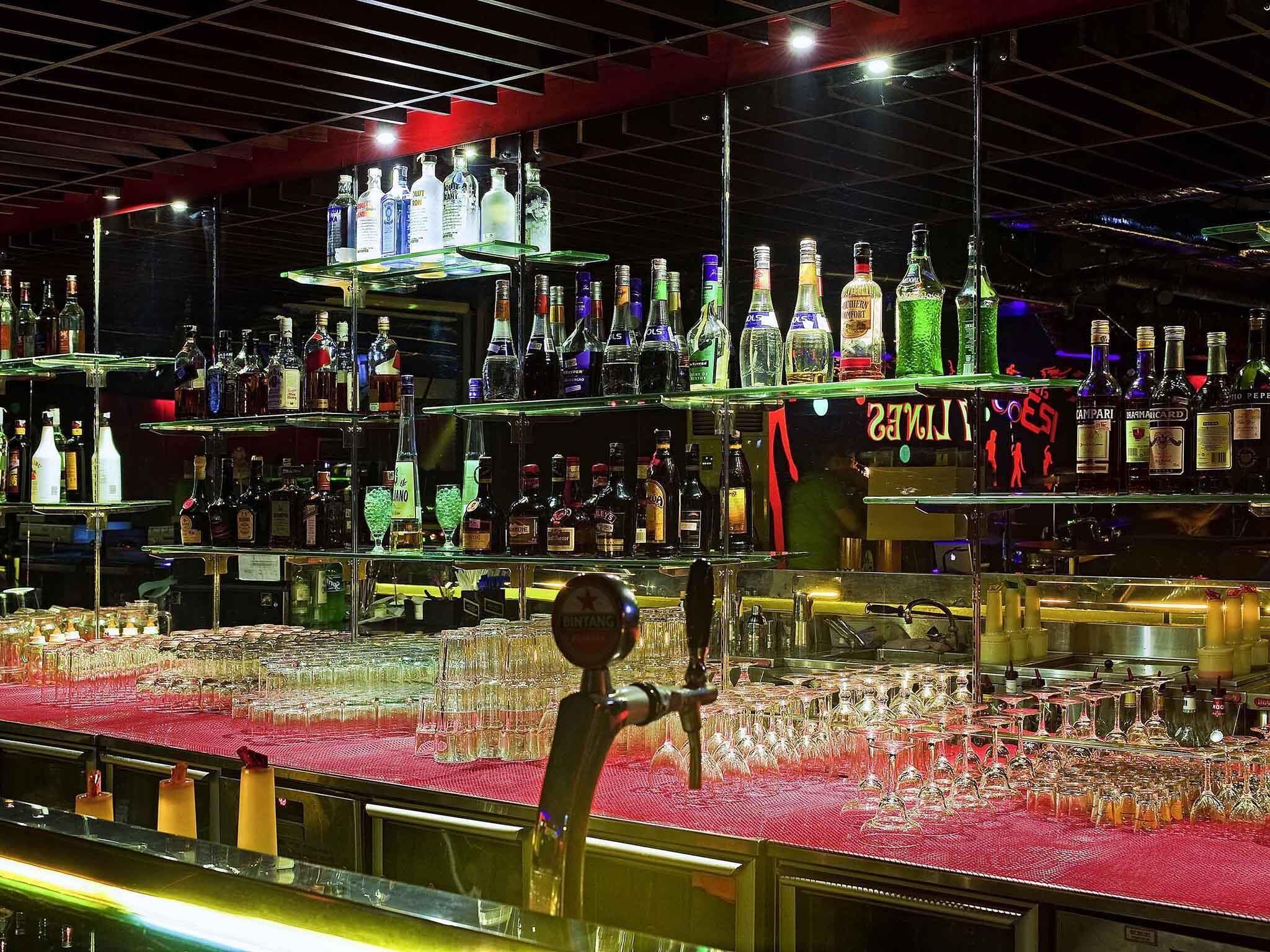 A bar area with multiple shelves stocked with various bottles and glasses.