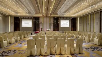 A conference room with rows of chairs, a carpeted floor, and a chandelier.