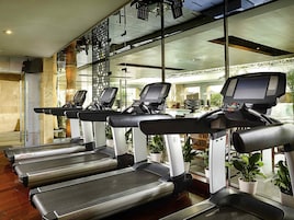 Un gimnasio con cintas de correr, una banca de pesas y una máquina de remo.