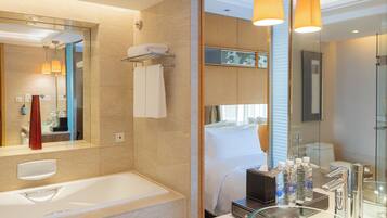 A modern bathroom with a large mirror, a bathtub, a glass shower enclosure, and a vanity with a sink and mirror.