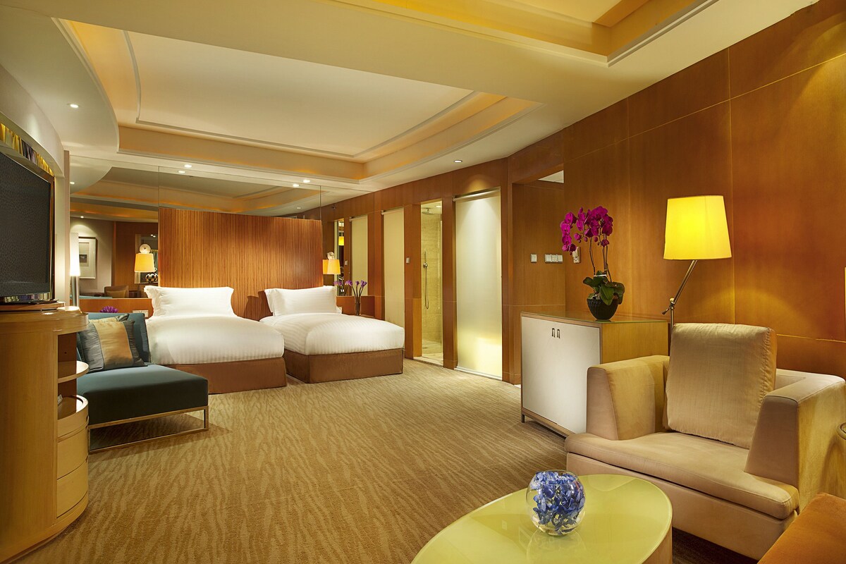 A hotel room with a large bed, a sofa, a desk, and a TV.