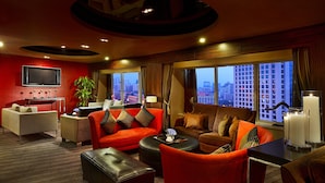 A modern hotel room with a red accent wall, a flat-screen TV, a sofa set, a coffee table, and a view of the cityscape through large windows. - Sofitel Xian on Renmin Square (Xi'an)