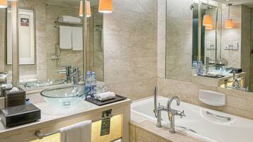 A modern bathroom with a glass bowl sink, a large mirror, and a bathtub.
