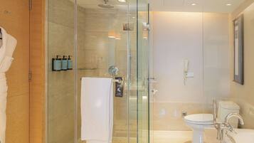 A modern bathroom with a glass-enclosed shower, a toilet, and a sink.