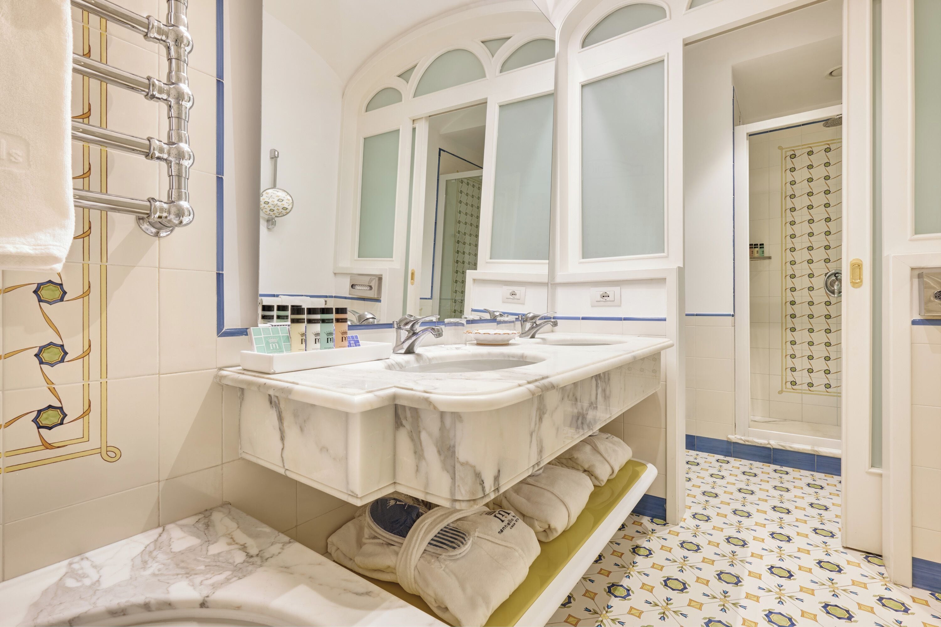 A bathroom with a double sink, a towel rack, and a shower area.